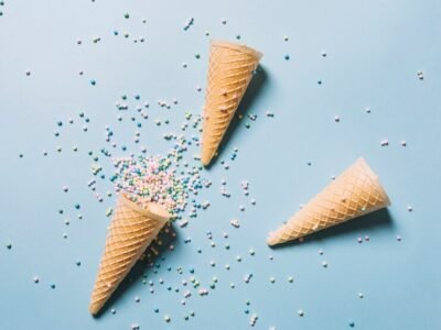 elevated-view-colorful-sprinkles-with-waffle-cones-blue-background_23-2147957486